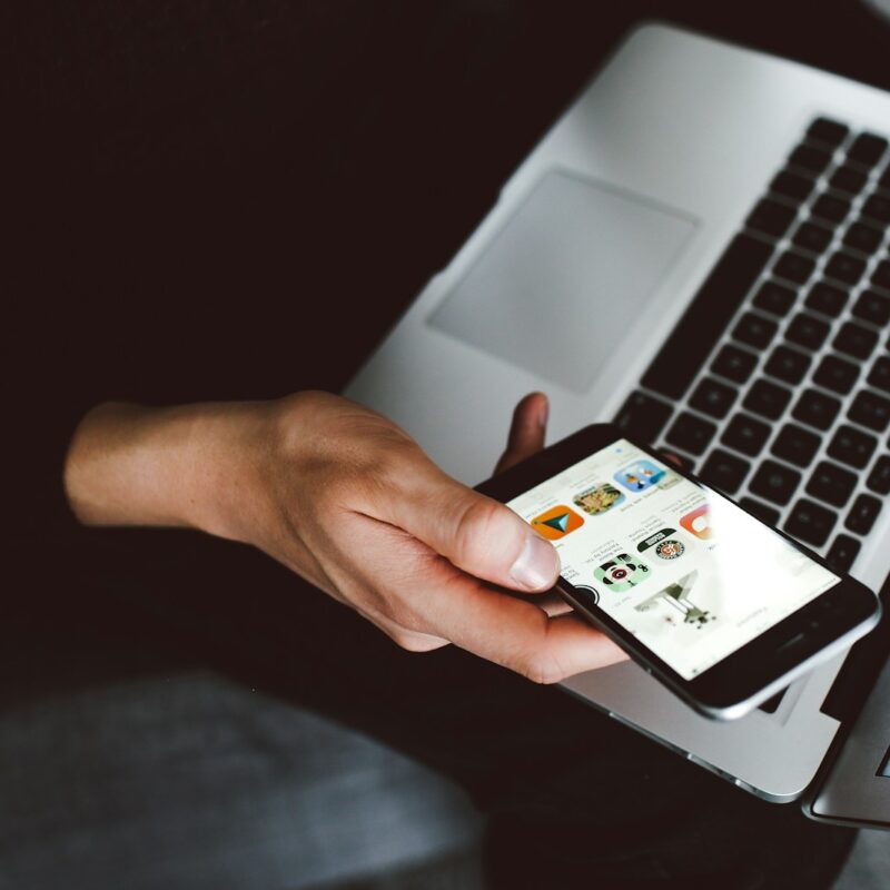 person holding smartphone and laptop