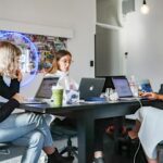 3 women sitting on chair in front of table with laptop computers