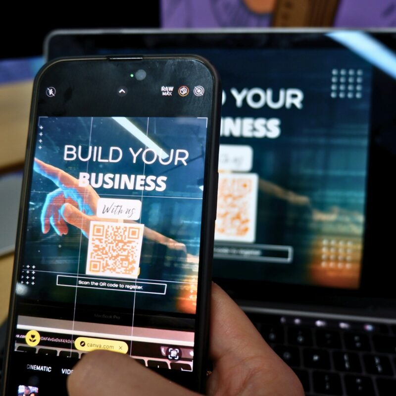 a person holding a cell phone in front of a laptop