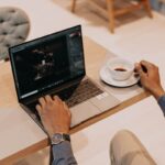 person using macbook pro on white table